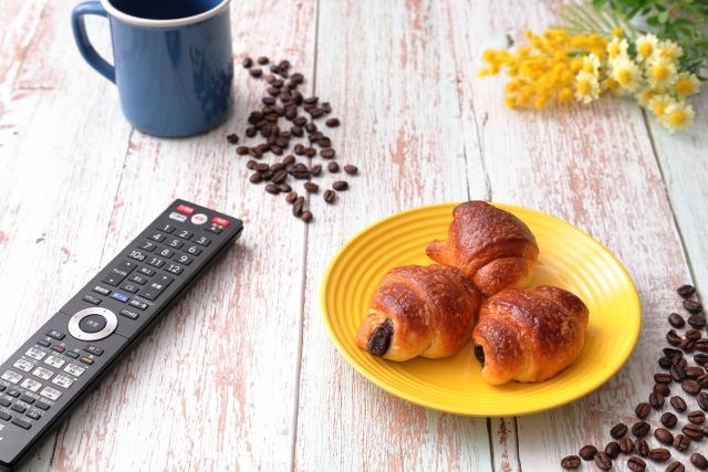 朝食とテレビのリモコン｜忙しい朝のイメージ